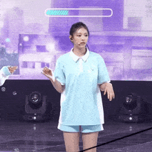 a girl in a blue shirt and shorts stands on a stage with a loading bar above her head