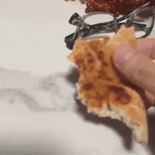 a person holding a piece of food with a pair of glasses on top