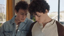 two young men with curly hair look at something
