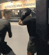 two men are boxing in front of a sign for authentic mma training