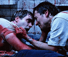 two men are laying on the floor with blood on their bodies