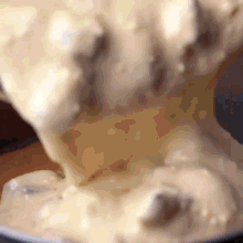 a close up of a person pouring a creamy substance into a bowl