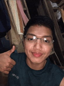 a young man wearing glasses is giving a thumbs up and wearing a shirt that says onaler