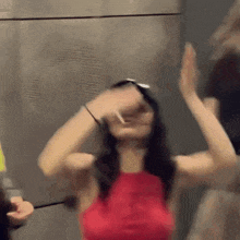 a woman in a red top is dancing with her hands in the air