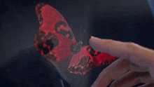 a person 's finger is pointing to a red object