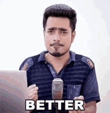 a man with a beard is holding a microphone in front of a laptop and says `` better '' .