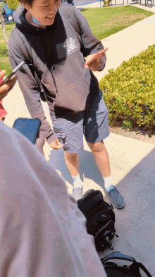 a man wearing a hoodie with a lion on it is looking at his phone