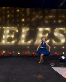 a woman in a blue dress is running on a stage in front of a large sign that says ez