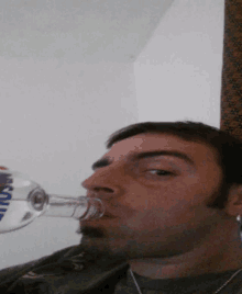 a man is drinking from a bottle that has the word smirnoff on it
