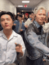 a group of people standing in a hallway with a red exit sign in the background