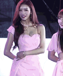 a woman in a pink dress is standing next to another woman in a white dress