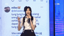 a girl is standing in front of a screen that says milaaa