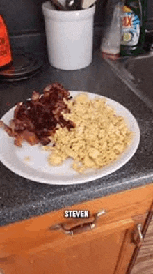 a white plate topped with scrambled eggs and bacon on a counter .