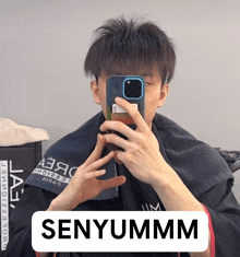 a man is taking a picture of himself with a cell phone and the caption says senyummm