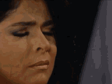 a close up of a woman covering her mouth with her hand .