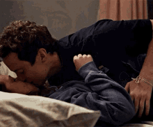 a man and a woman are kissing in bed .
