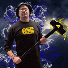 a man wearing a black shirt that says o2e is holding a hammer