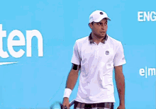 a man in a white shirt is holding tennis balls in front of a rakuten sign