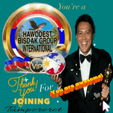 a man in a tuxedo holds an award in front of a sign that says ' hawedest bisdak group international '