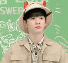 a young man wearing a safari hat and a scarf with the word sweer written on the back