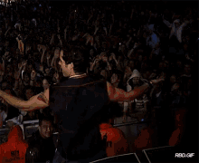 a man stands in front of a crowd wearing an orange jacket that says 911 on it