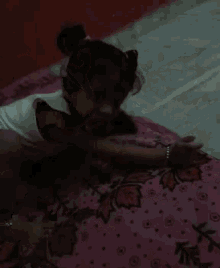 a little girl is laying on a pink blanket with leaves on it