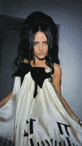 a woman with long black hair is wearing a white dress with black letters that says " it "