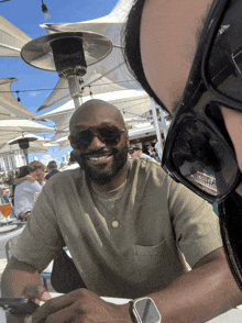 a man wearing sunglasses sits at a table with a woman wearing sunglasses