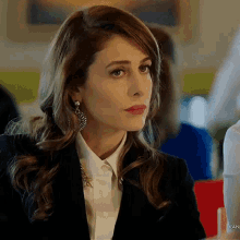 a woman wearing a white shirt and a black jacket is sitting at a table .