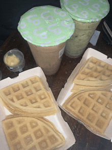 two boxes of waffles sit on a table next to two cups of tea
