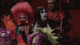 a drag queen with a candy cane in her mouth is standing next to another drag queen