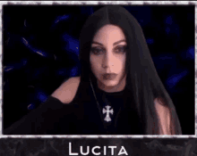 a woman with long black hair and a cross necklace is giving an ok sign .