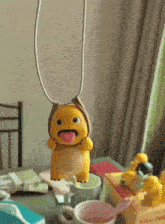 a yellow stuffed animal with a tongue sticking out is sitting on a table