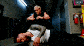 two men are wrestling in a hallway while one of them is laying on the floor .