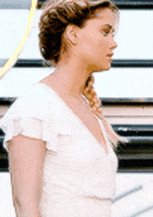 a woman in a white dress is standing in front of stairs