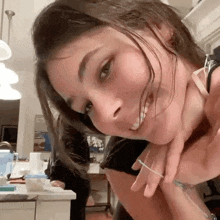 a close up of a woman 's face with her hand on her neck and a ring on her finger .