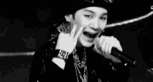 a black and white photo of a young man holding a microphone .