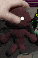 a person 's hand is touching a stuffed animal that looks like a monster