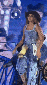 a woman wearing a cowboy hat and jeans is standing on a stage