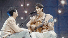 a man singing into a microphone while another man plays guitar