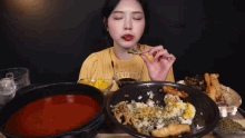 a woman in a yellow shirt is eating a piece of food