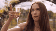a woman is holding a glass of champagne and pointing at it
