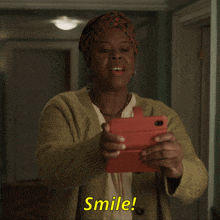 a woman is smiling while holding a cell phone and the word smile is on the screen
