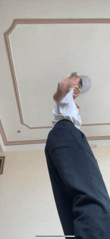 a man in a white shirt and black pants stands in front of a white ceiling
