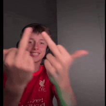 a young man wearing a red lfc shirt shows his middle finger