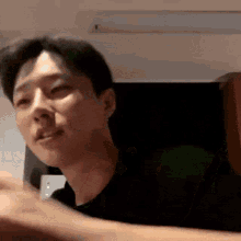 a man in a black shirt is making a funny face while sitting at a table .