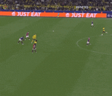 soccer players on a field with a just eat advertisement