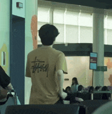 a man wearing a stussy t-shirt stands in an airport