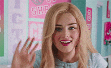 a woman with blonde hair is waving her hand in front of a sign that says ice cream .