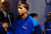 a man wearing a blue jacket that says bingx